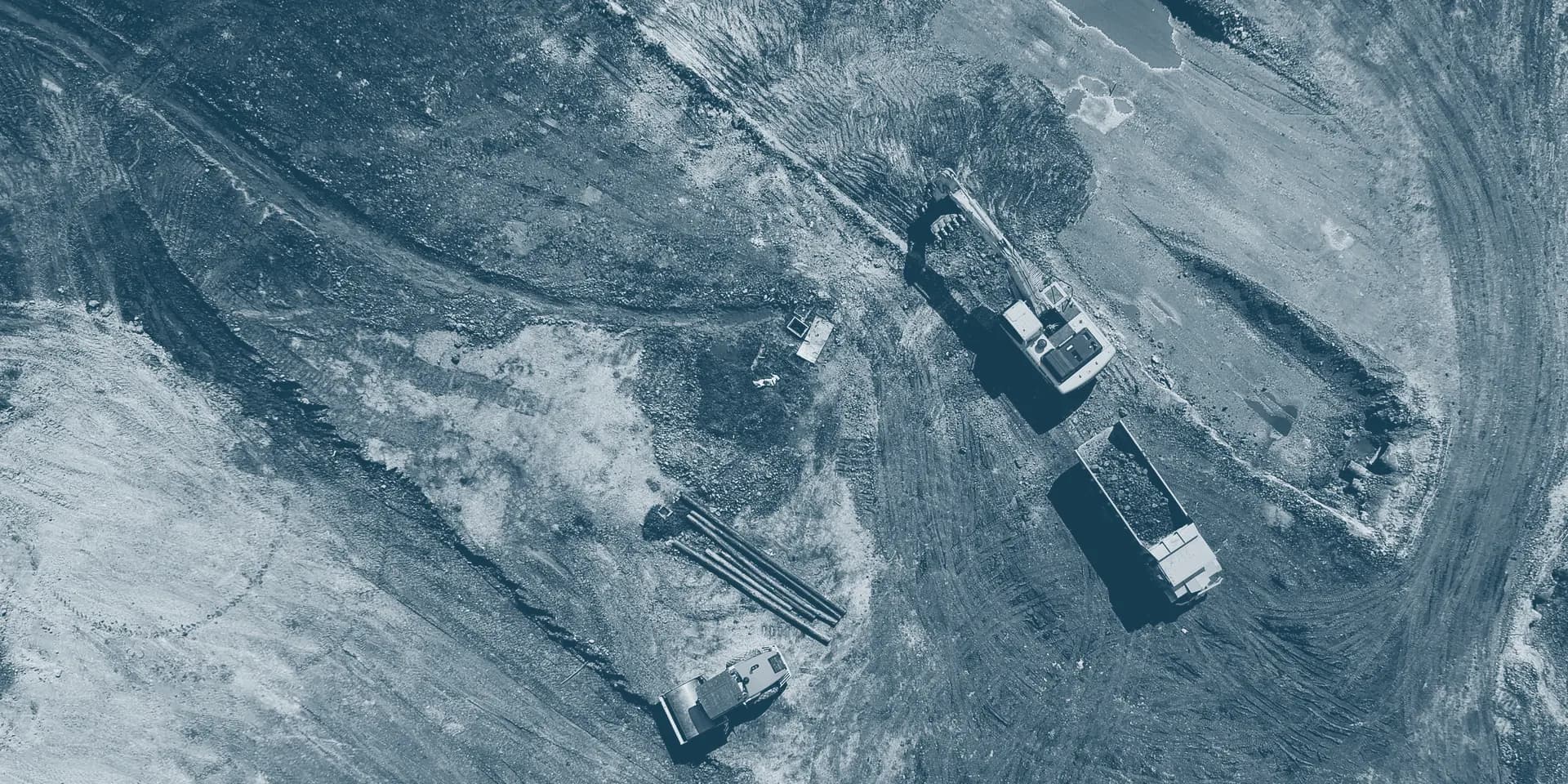 Vista aérea de uma escavadeira hidráulica carregando um caminhão basculante em um canteiro de terraplenagem.